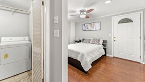 A bedroom with a bed, a ceiling fan, a door, and a laundry area with a washing machine.