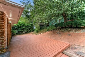 Um deck de madeira com um muro de tijolos e um muro de pedra ao fundo.