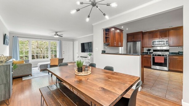 A modern kitchen with wooden cabinets, stainless steel appliances, and a dining area with a wooden table and benches.