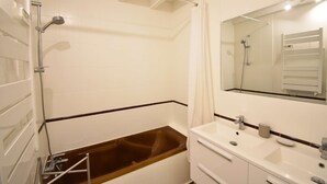 Une salle de bain avec une baignoire, une douche et un lavabo avec un miroir.