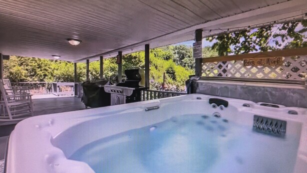 Een hottub met een houten terras en een bordje met de tekst 'Bees aan het werk'.