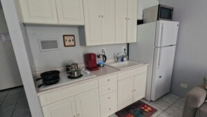A compact kitchen with white cabinets, a microwave, a sink, and a coffee maker. - 407 ❤️LOCATION❤️ 5min to 🏄♀️🏊♀️🐠🦈🌸 free parking 🚙🅿️, fast WIFI💻 (Honolulu)