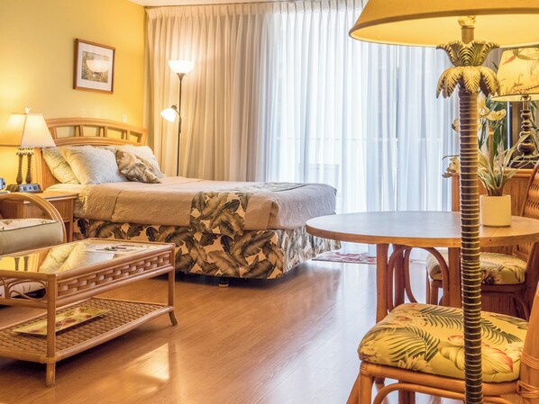 Een hotelkamer met een bed, een ronde tafel, een stoel, een lamp en een kamerplant.