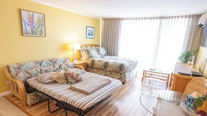 Una habitación con una cama, un sofá, una mesa de vidrio y una silla.
