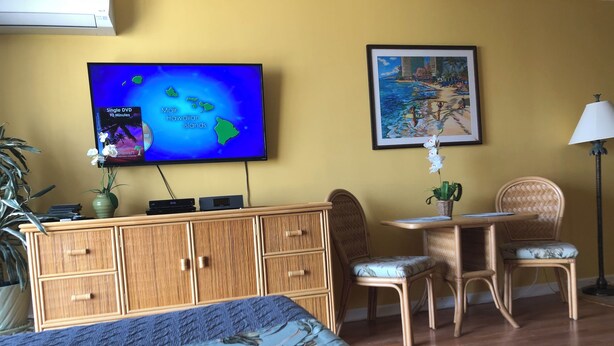 A hotel room with a bed, a wooden desk, a chair, a television displaying a map, a framed picture on the wall, and a potted plant. - 💎LOCATION💎 5min to 🏄‍♀️🏊‍♀️🐠🦈🌸 free parking 🚙🅿️, fast WIFI💻 🌺F15A06🌺 (Honolulu)