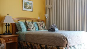 A neatly made bed with floral-patterned bedding, a bedside lamp, and a small table with a lamp. - 💎LOCATION💎 5min to 🏄‍♀️🏊‍♀️🐠🦈🌸 free parking 🚙🅿️, fast WIFI💻 🌺F15A06🌺 (Honolulu)