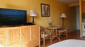 A room with a television, wooden cabinet, wicker chairs, a small table with a potted plant, and a painting on the wall. - 💎LOCATION💎 5min to 🏄‍♀️🏊‍♀️🐠🦈🌸 free parking 🚙🅿️, fast WIFI💻 🌺F15A06🌺 (Honolulu)