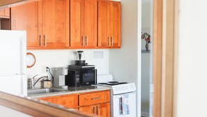 Une cuisine avec des meubles de rangement en bois, un four à micro-ondes, une machine à café et une cuisinière.