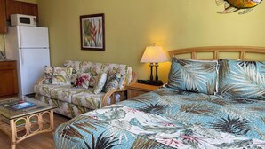 Ein Zimmer mit einem Bett, einem Schlafsofa, einem kleinen Tisch, einer Lampe und einer Wanddekoration mit Fischmotiven.