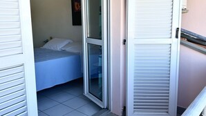 Un dormitori amb un llit, una porta corredissa de vidre i un tancament blanc apariat.