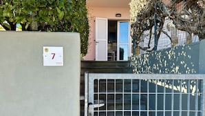 Una entrada protegida con un letrero con número, una escalera y un edificio con una puerta abierta.