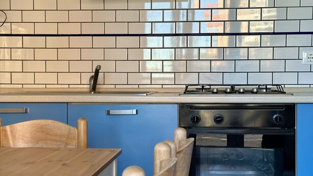 Una cocina con salpicadero de azulejos, estufa, horno y una mesa de madera.