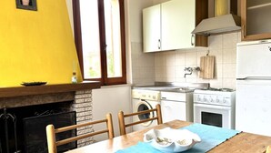 Una cocina con mesa, sillas, lavadora, estufa y armarios.