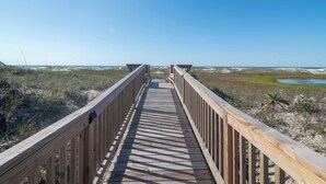 A wooden boardwalk leading to beach huts with a clear view of the ocean. - Hobbs Realty - "All that Jazz" includes a private pool & panoramic views! (Holden Beach)