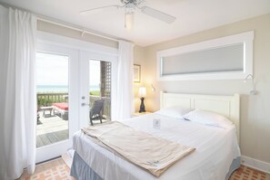 Relax in comfort with a large bed, ceiling fan, and a view of the outdoors.