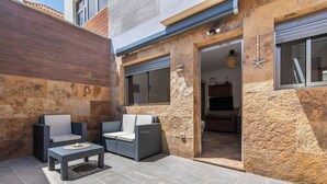 An outdoor seating area with wicker furniture and a stone wall. - Home2Book Cozy Apt 2 Min From La Garita Beach (La Garita)