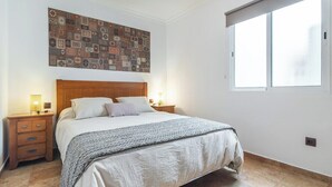 A bedroom with a wooden headboard, a large bed with white bedding, two bedside tables with lamps, and a large window with a blind. - Home2Book Cozy Apt 2 Min From La Garita Beach (La Garita)