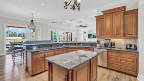 A spacious kitchen with wooden cabinets, granite countertops, and a large island.