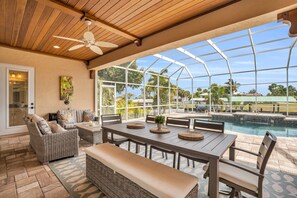 Relax in this serene outdoor space with a pool view, dining area, and comfortable seating.