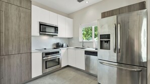 A modern kitchen with stainless steel appliances, white cabinetry, and a window providing natural light. - Home LifeStyle Miami
Downtown and Miami Beach  (Miami)