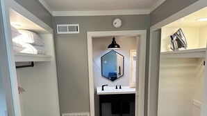 A narrow hallway with bunk beds on either side, a central bathroom with a mirror and sink, and a radiator on the floor.