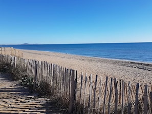 A beach with a wooden fence and a clear view of the ocean.