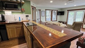 A kitchen with a central island, wooden cabinets, a microwave, and a sink. - Waterfront Studio with Hot Tub & Fire Pit Sleeps 4 (Eufaula)