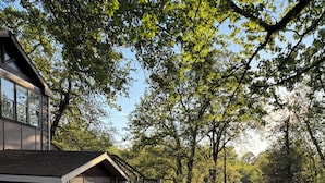 A rustic building with a gravel driveway, wooden porch, and a sign indicating 'The Studio.' - Waterfront Studio with Hot Tub & Fire Pit Sleeps 4 (Eufaula)