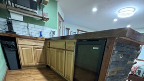 A kitchen with wooden cabinets, a built-in microwave, and a stone accent wall.