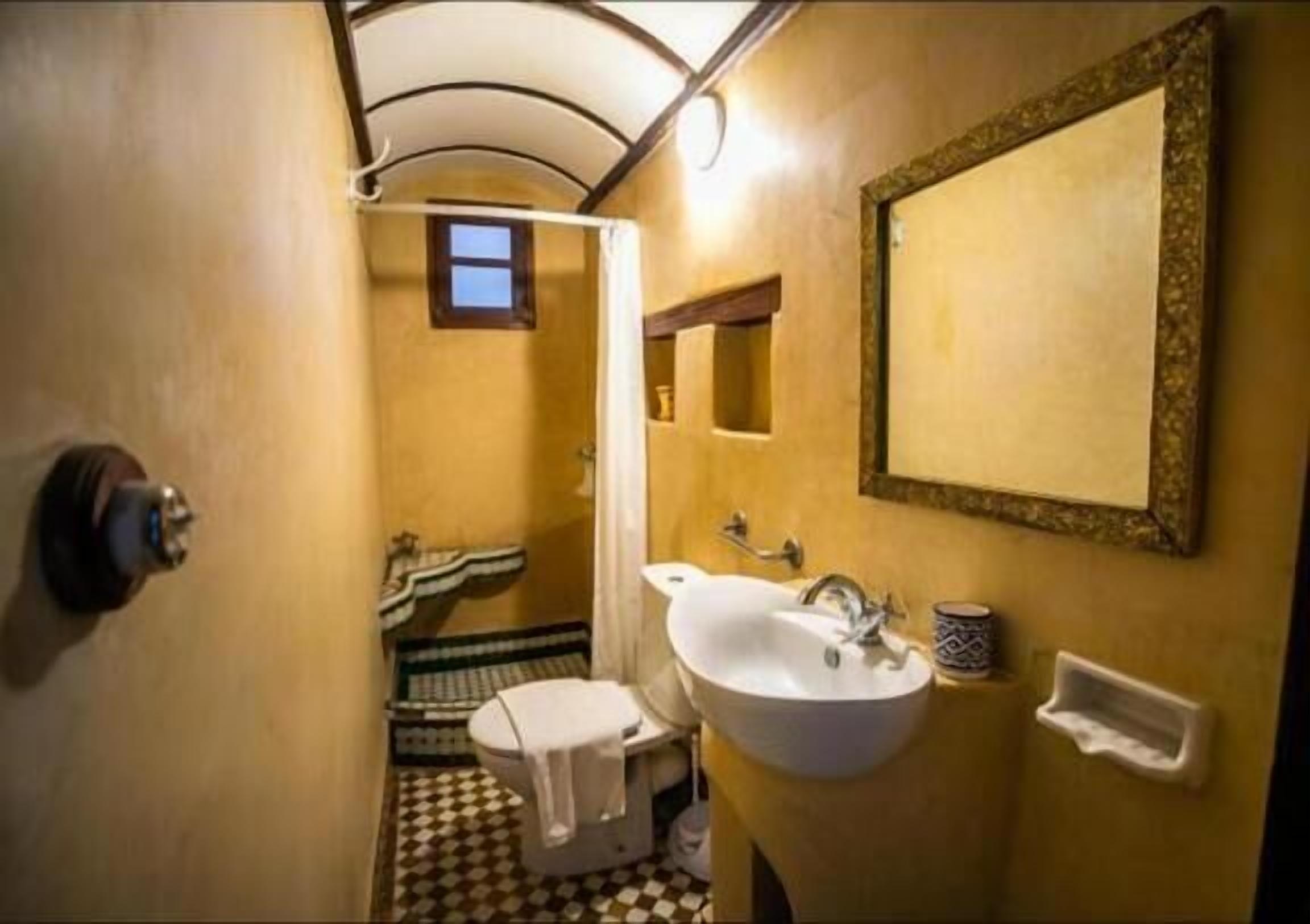 Une petite salle de bain avec un lavabo blanc, un miroir et des toilettes.