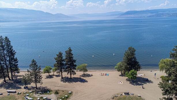 A beach with a clear view of the water and mountains in the distance.