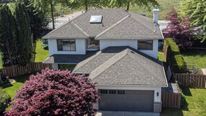 A two-story house with a garage, surrounded by a well-maintained lawn and trees.