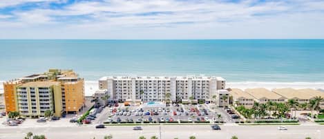 Un hotel con varias construcciones, estacionamiento y vista al mar.