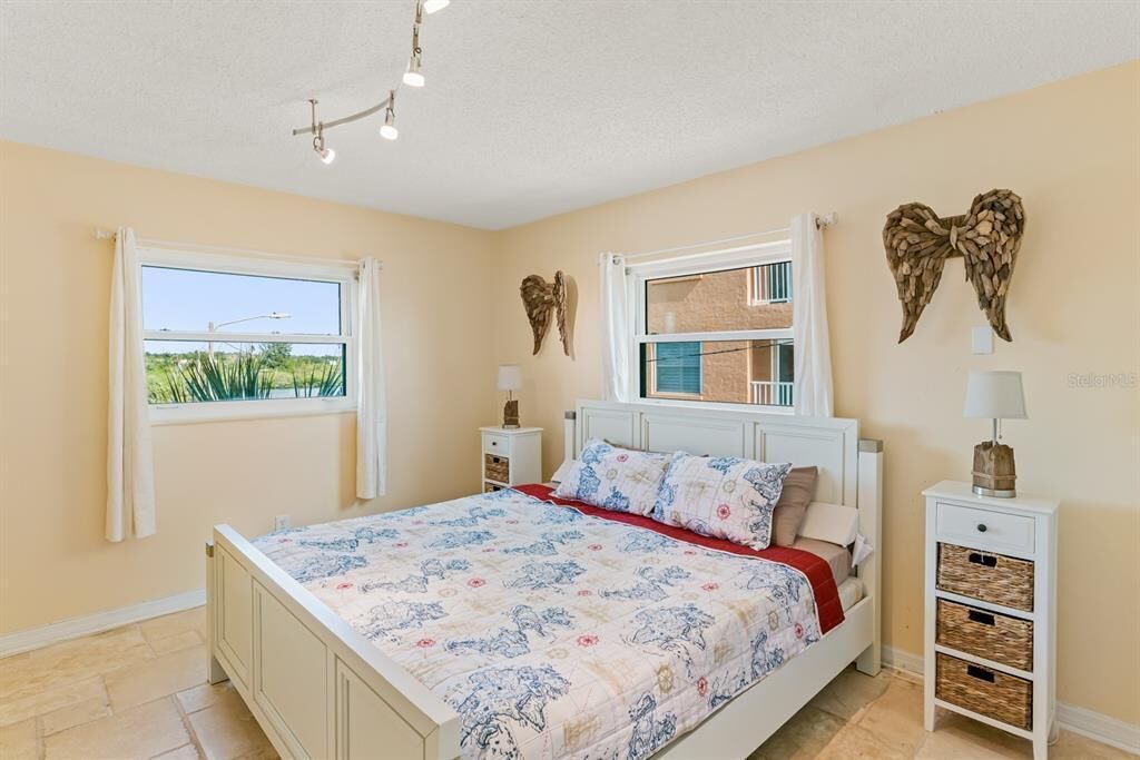 Une chambre à coucher comprenant un lit, deux tables de chevet, une fenêtre et des éléments décoratifs sur les murs.