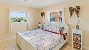Une chambre à coucher comprenant un lit, deux tables de chevet, une fenêtre et des éléments décoratifs sur les murs.