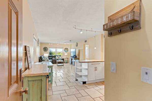 Un amplio espacio de sala con cocina, una mesa de comedor y un sofá. Hay un letrero que dice 'WELCOME'.