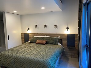 Relax in a serene bedroom with a large bed, patterned bedspread, and comfortable pillows.