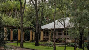 A rustic building with a covered porch, surrounded by lush greenery and trees.