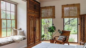 Une chambre avec une grande fenêtre, une armoire en bois et une chaise placée près de la fenêtre.