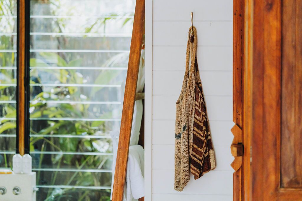 Une pièce avec une porte en bois, une fenêtre avec des stores et une serviette suspendue.