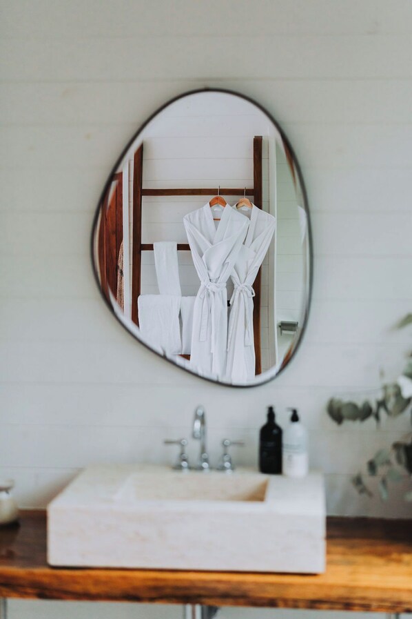 A bathroom with a round mirror, white sink, and wooden countertop.