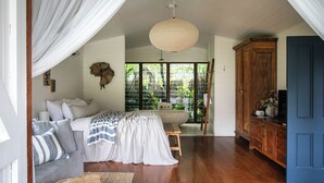 Un dormitorio amplio con una cama grande, un armario de madera y vistas al verdor por la ventana.