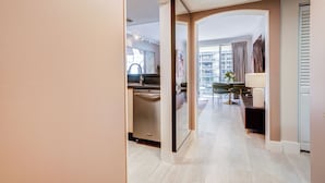 Habitación de hotel moderna con cocina, una mesa de comedor y sillas, y vistas a la ciudad a través de amplios ventanales.