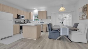 Et moderne køkken med træskabe, en central ø og et spiseområde med bord og stole.