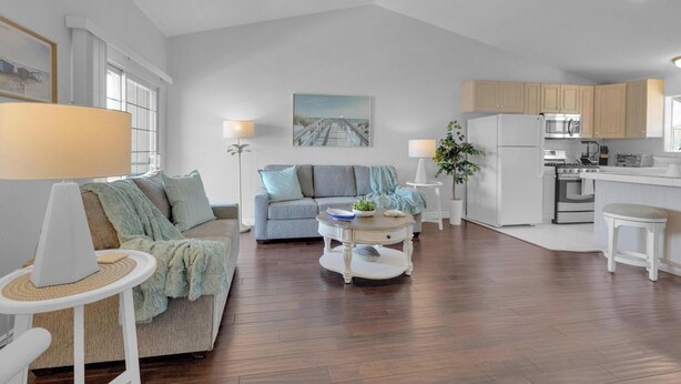 A modern living room with a grey sofa, a round coffee table, and a dining area with a white refrigerator and stove. - Bright, Spacious 2BD/2BA in the Heart of Hillcrest (San Diego)