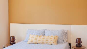A bedroom with a bed, two bedside lamps, a ceiling fan, and a plain wall.