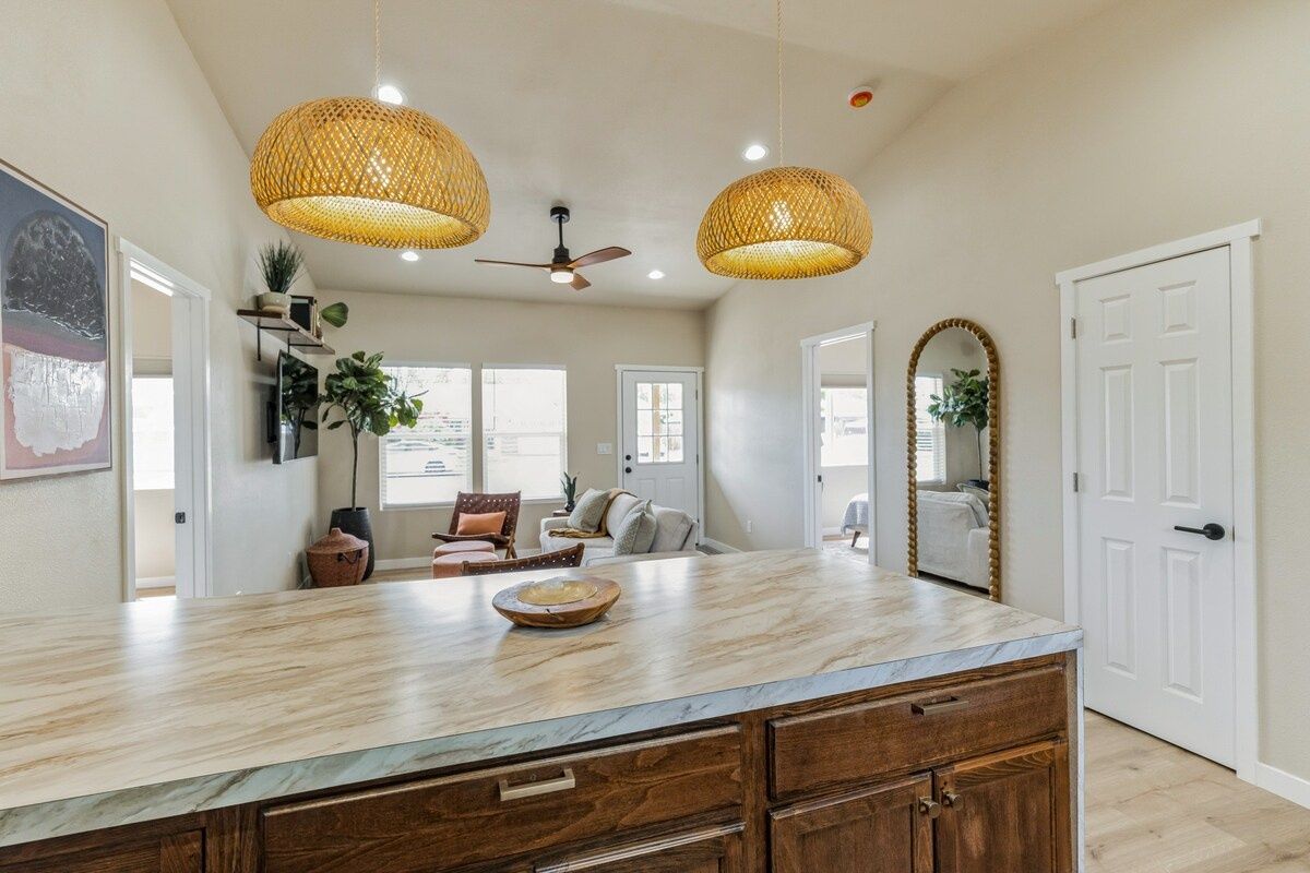 A spacious kitchen with a marble countertop, wooden cabinets, and a ceiling fan.