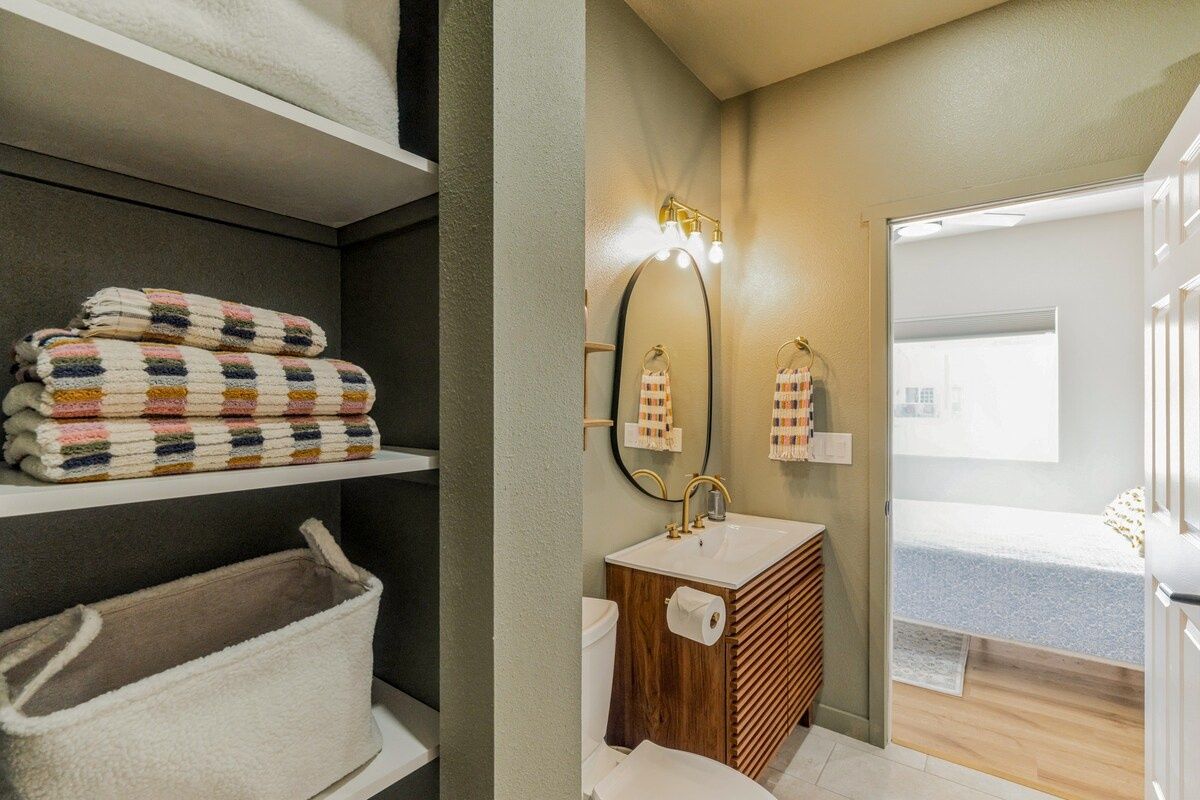 Bright bathroom entrance with vanity and organized linen storage.