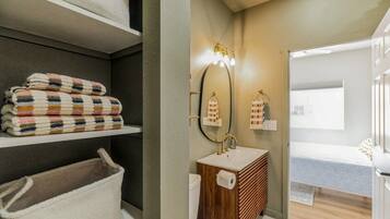 Bright bathroom entrance with vanity and organized linen storage.