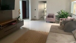 Ein modernes Wohnzimmer mit Flachbildfernseher, einer Couch, einem Couchtisch und einem Topfpflanzen.